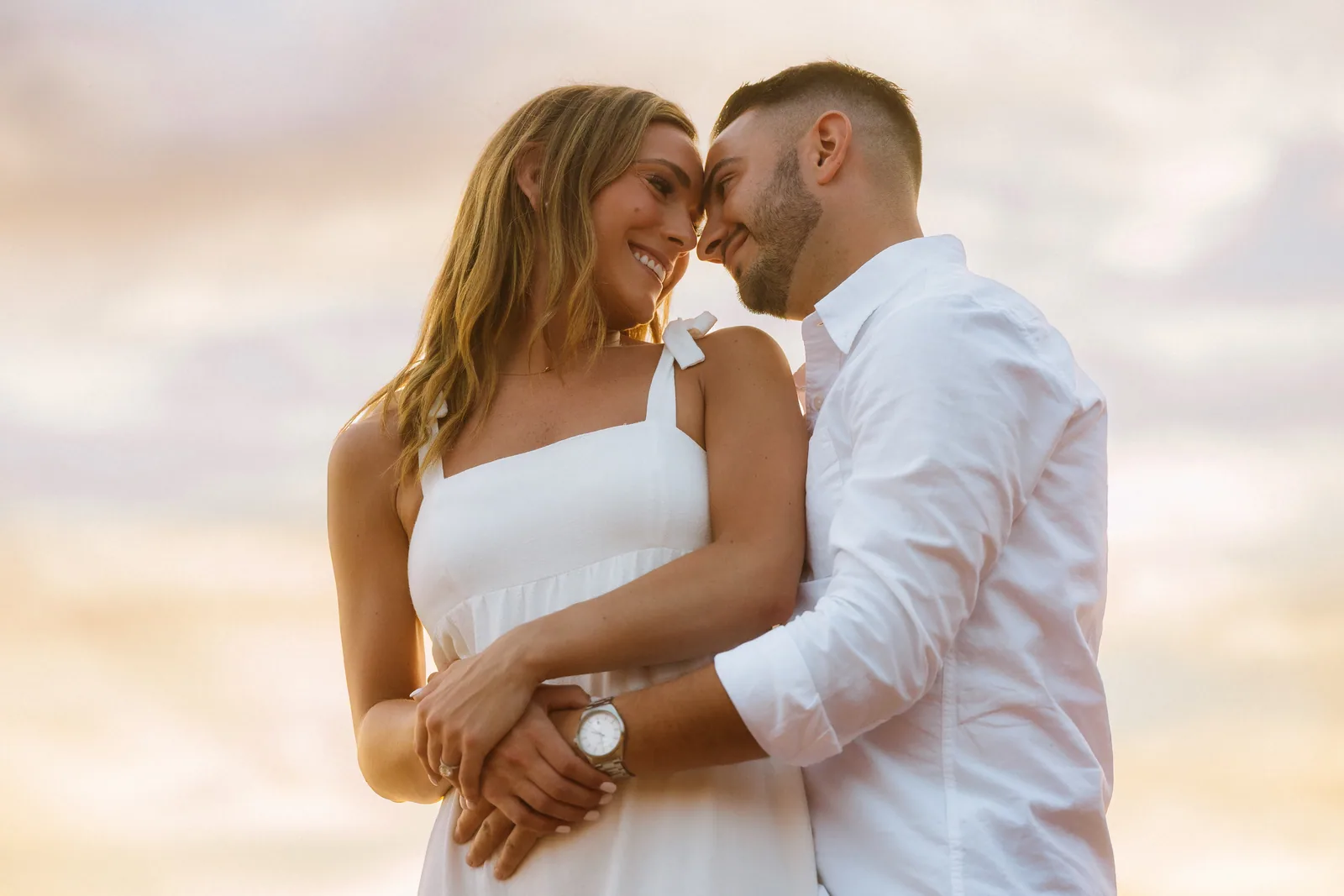 A couple laughing close together in soft golden light on the beach