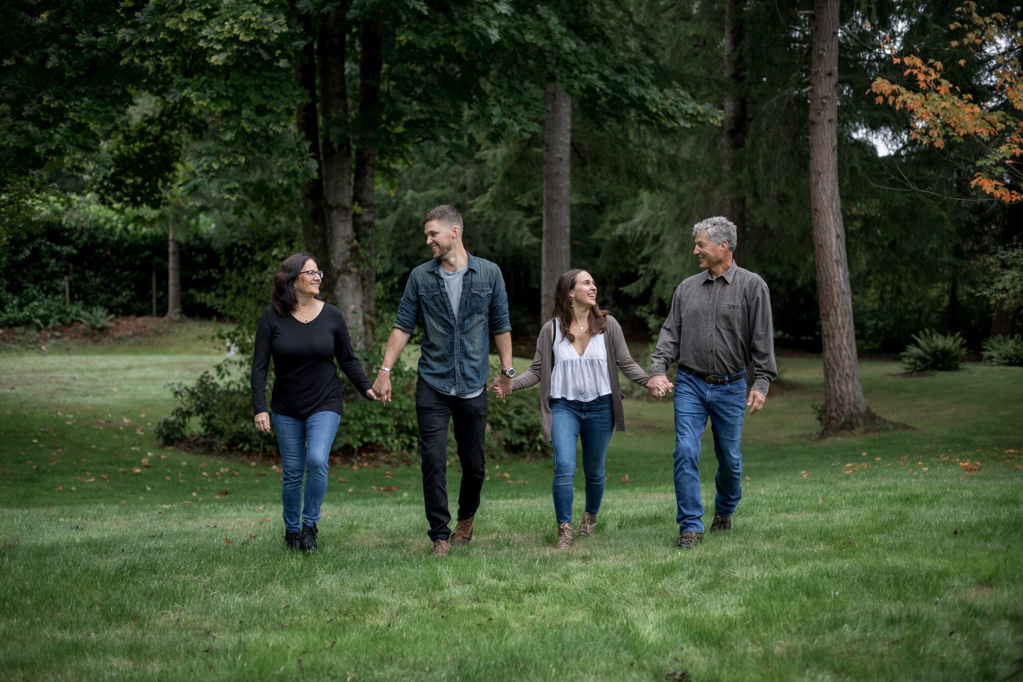 Jessie Hawaii Photography, Happy family of four walking hand-in-hand in a park.