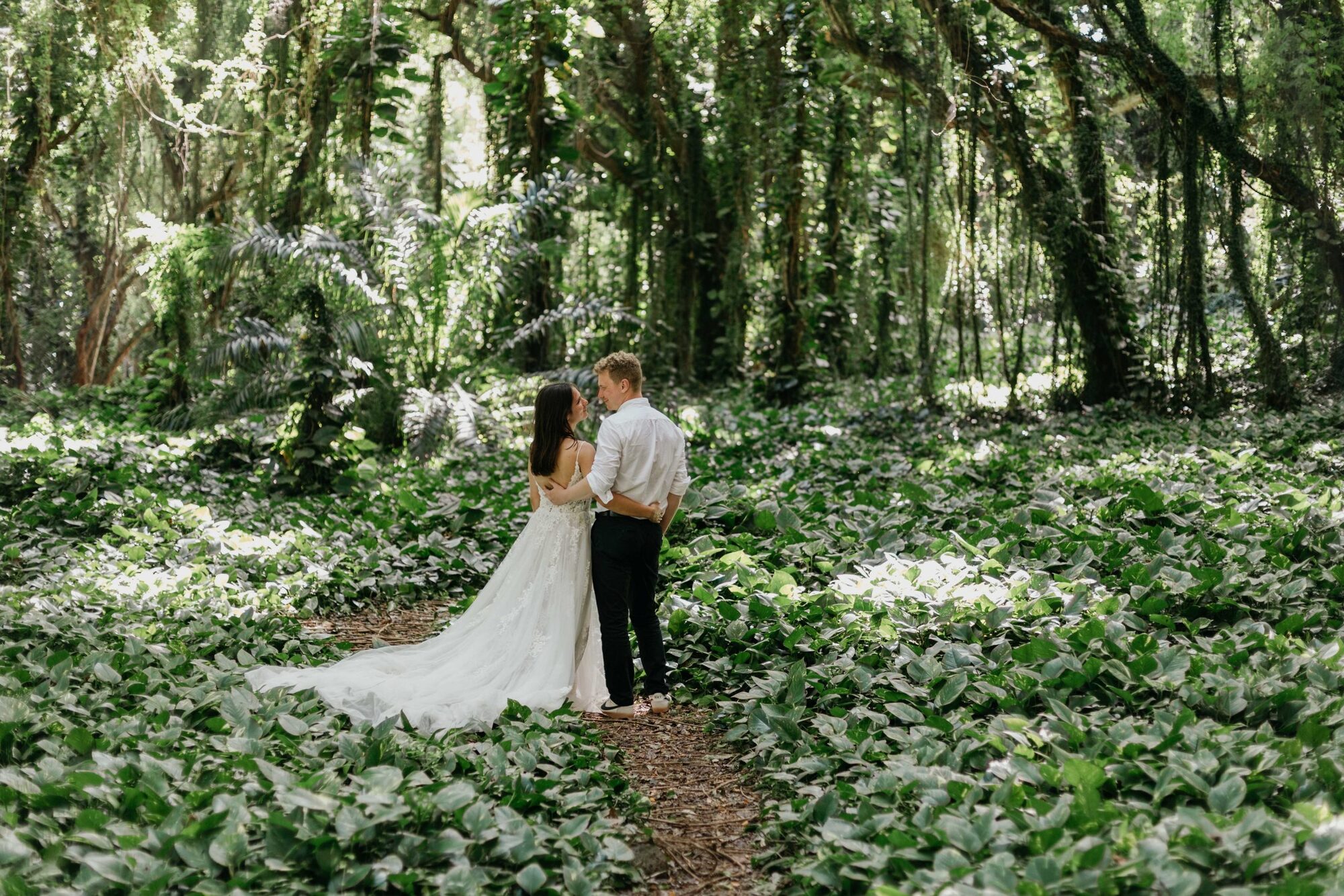 Jessie Hawaii Photography, Bride and groom embrace in lush green forest, wedding photography