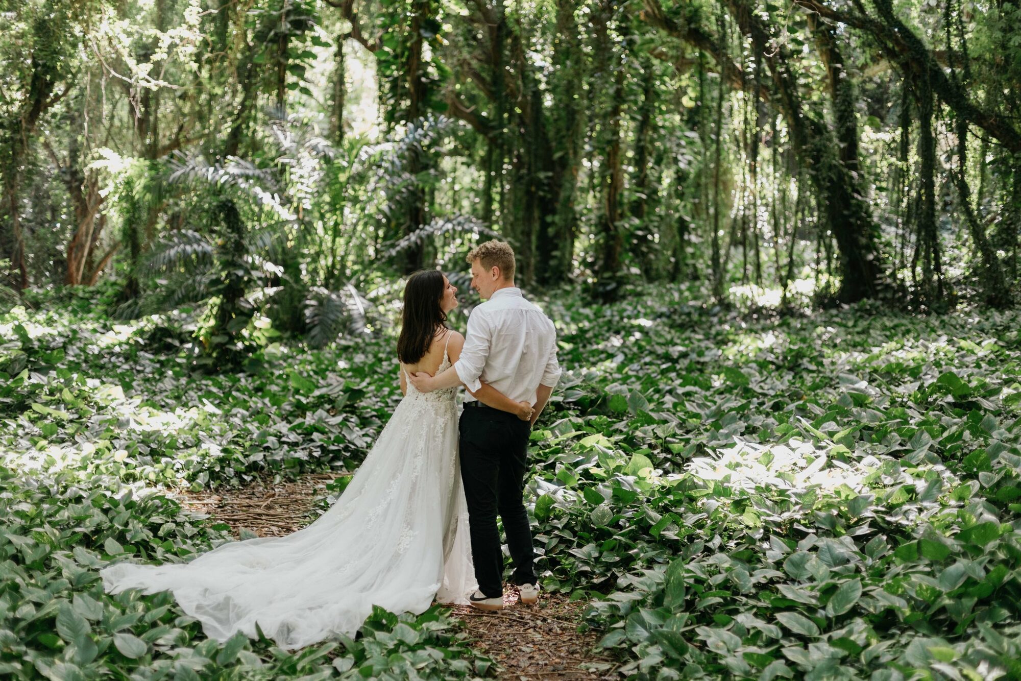 Jessie Hawaii Photography, Bride and groom embrace in lush green forest. Wedding photography.
