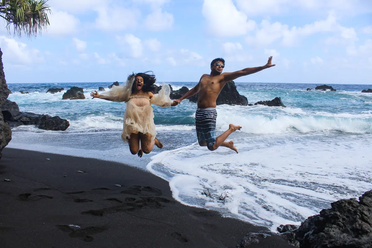 Two guests jumping in the surf on a black sand beach