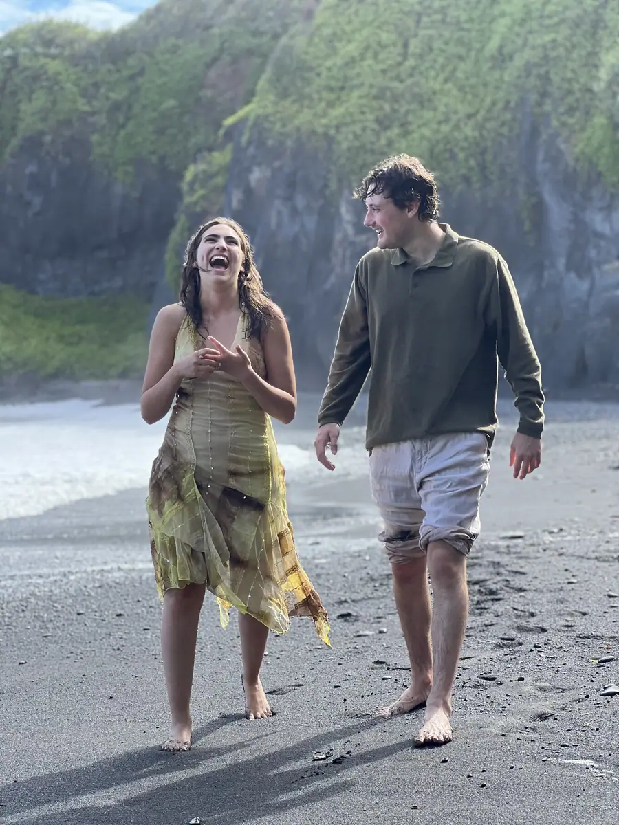 A couple walking a black sand beach together