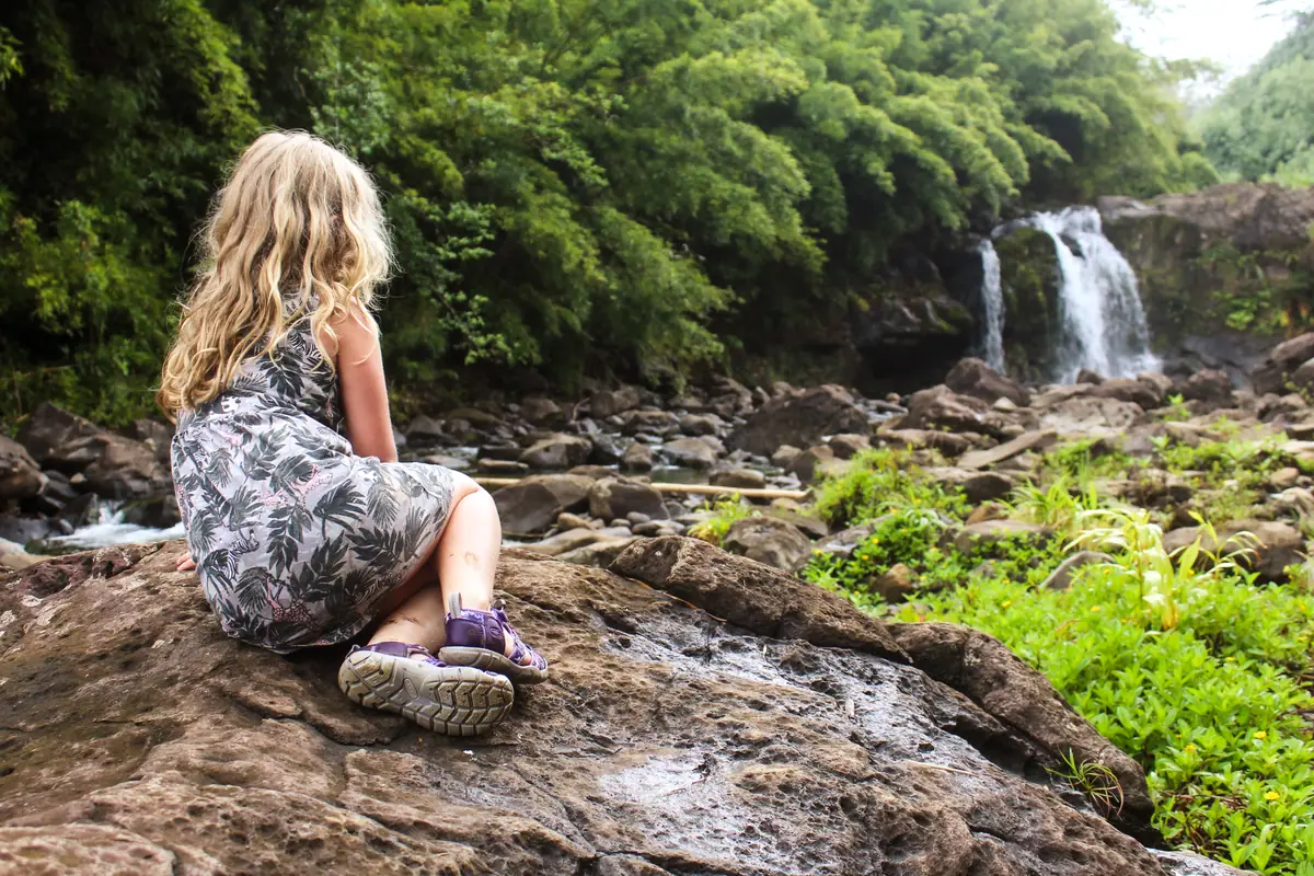 A guest sitting on the rocks beside a stream and waterfall